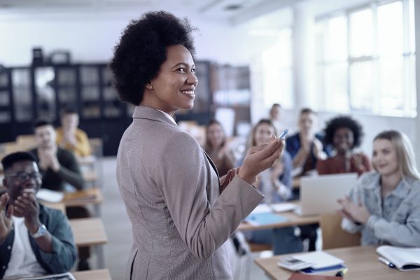 African-American professor receives applause from her students as she gives them a lecture in class.