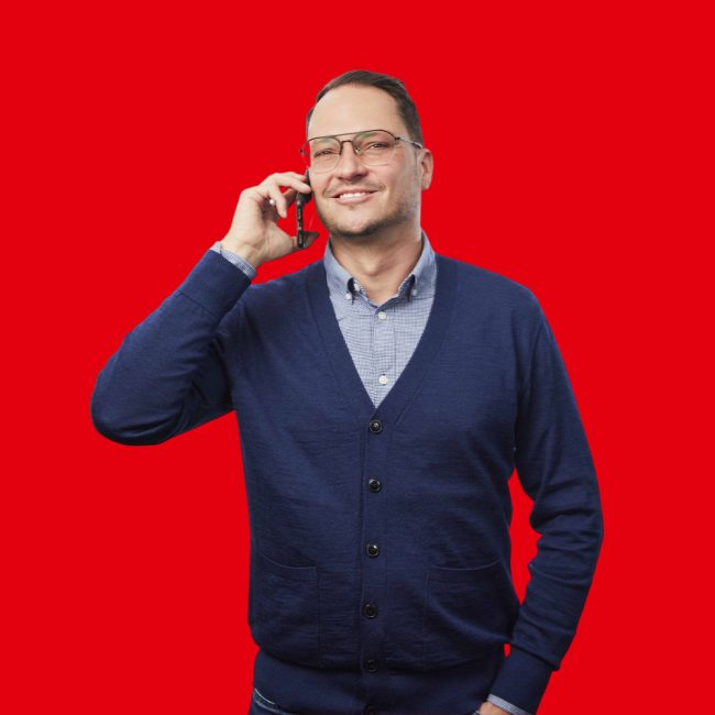 Franklyn-Wolf gentleman wearing a dark blue waistcoat and light blue blouse holding a phone